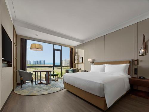 a hotel room with a bed and a desk and a table at Doubletree By Hilton Yantai Golden Coast Hotel & Suites in Yantai