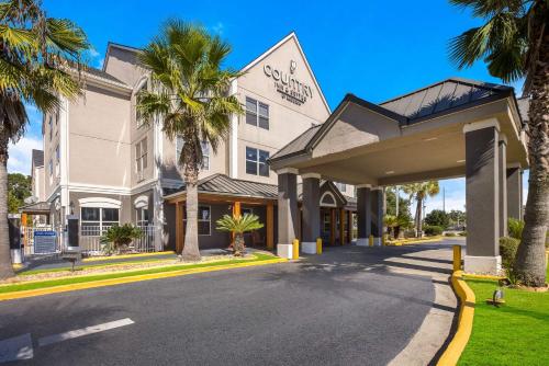 a building with palm trees in front of a street at Country Inn & Suites by Radisson, Hinesville, GA in Hinesville