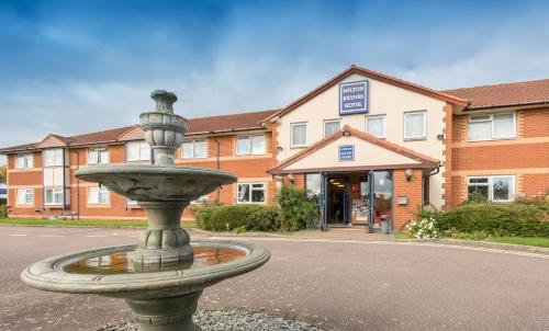 a fountain in the middle of a street in front of a building at MK Hotel in Stony Stratford