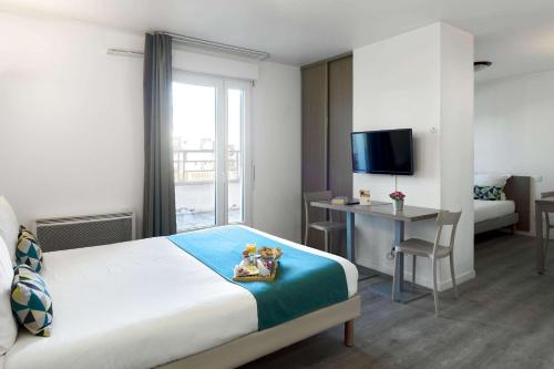 Schlafzimmer mit einem Bett, einem Schreibtisch und einem TV in der Unterkunft Comfort Aparthotel Versailles, St Cyr l'Ecole in Saint-Cyr-lʼÉcole
