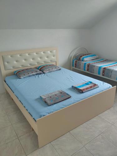 two beds in a bedroom with blue sheets and pillows at Apartament Timi in Golem