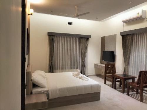 Dormitorio con cama, escritorio y TV en Coorg Riverness Resort, en Kushālnagar