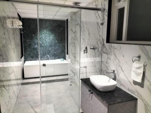 y baño con ducha, lavabo y bañera. en Coorg Riverness Resort, en Kushālnagar