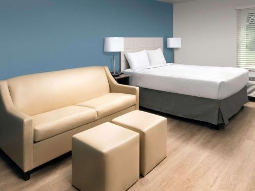 a hotel room with a bed and a couch at WoodSpring Suites Huntsville - Research Park in Huntsville