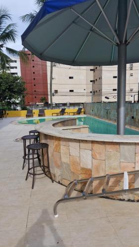 a table and chairs under an umbrella next to a pool at VICTORY FLAT-APTO 207 in Cabedelo