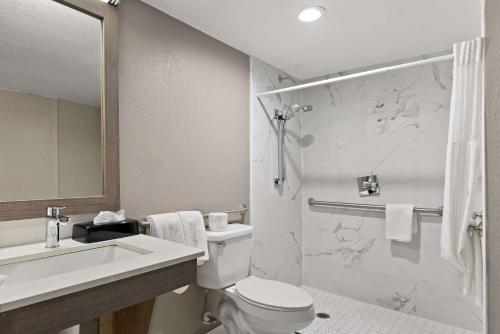 a bathroom with a toilet and a sink and a shower at Quality Suites Wildwood - The Villages in Wildwood