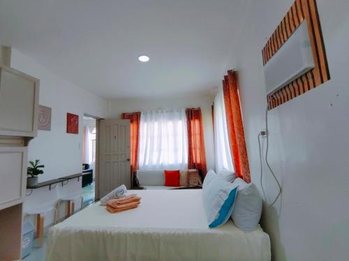 a bedroom with a white bed with orange curtains at HOST HOMES-SANDY LANE in Tacloban