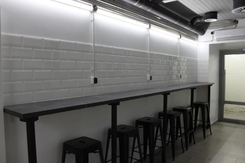 a long counter with stools in a room with white tiles at AV-3 capsule hotel in Kyiv