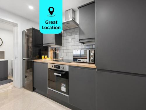 a kitchen with black appliances and a green sign that says great location at Modern Cozy 1 Bedroom Flat in Prime Location in Moseley in Birmingham