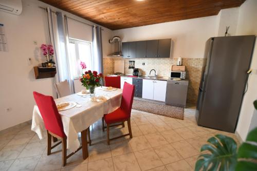 eine Küche mit einem Tisch mit roten Stühlen und einem Kühlschrank in der Unterkunft Holliday House Marko in Hrvace