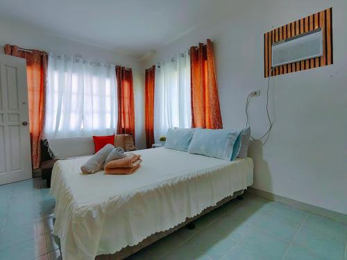 a bedroom with a large bed with orange curtains at HOST HOMES-SANDY LANE in Tacloban