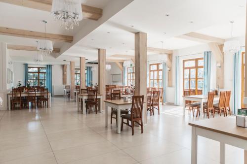 オストルフ・ビエルコポルスキにあるHotel i Restauracja Borowiankaのテーブルと椅子付きの広いダイニングルーム