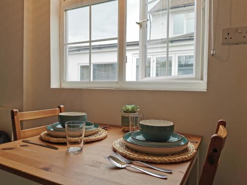 a wooden table with plates and dishes on it with a window at Selborne House in Havant