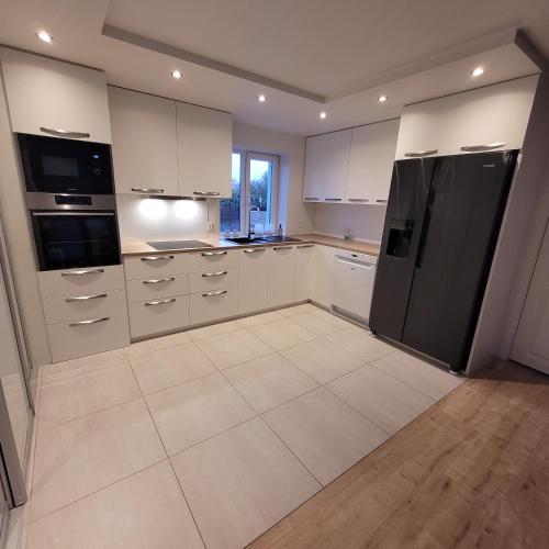 a kitchen with white cabinets and a black refrigerator at Sdr. Omme Bed & Breakfast in Sønder Omme