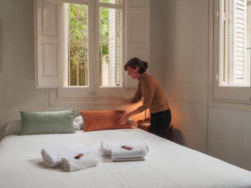 a woman standing next to a bed with three pillows at Verdi 254 in Barcelona
