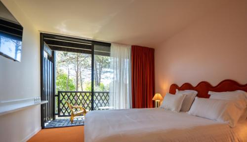 a bedroom with a bed and a large window at Boutique Hôtel La Baignoire in Lacanau-Océan