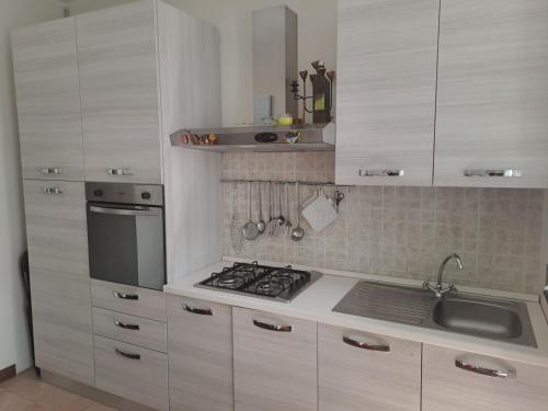 La cuisine est équipée de placards blancs, d'une cuisinière et d'un évier. dans l'établissement Appartamento Via Comune Antico, à Milan