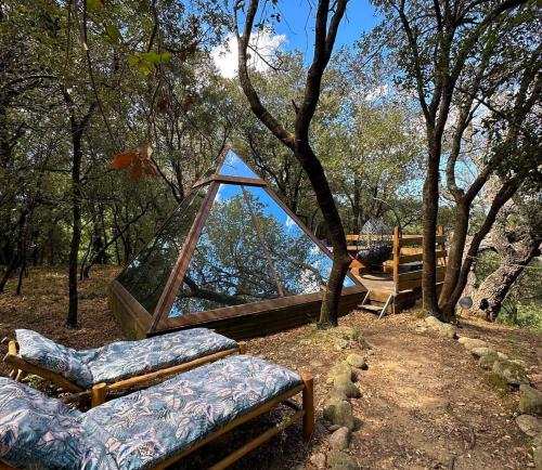 eine Hängematte im Wald mit Stühlen und einem Fenster in der Unterkunft Le mas cabanids in Maureillas