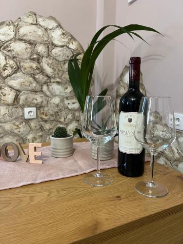 a bottle of wine and two wine glasses on a table at Spitaki in Alepou