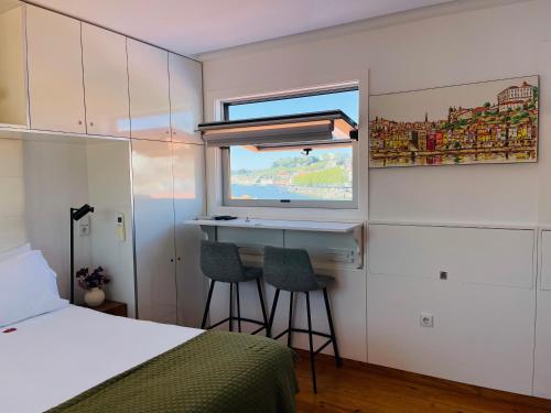 a bedroom with a bed and a desk and a window at Douro River Apartments in Vila Nova de Gaia