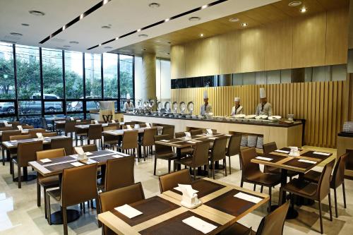 un restaurant avec des tables et des chaises en bois ainsi qu'un bar dans l'établissement Hotel The One, à Jeju