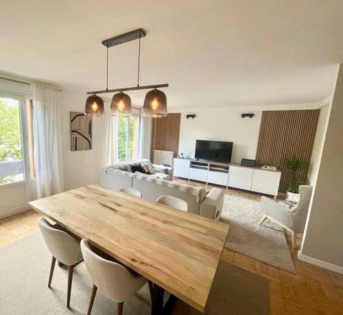 - un salon avec une grande table et des chaises en bois dans l'établissement Chambre dans appartement élégant proche de Paris, à Suresnes