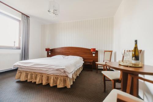 オストルフ・ビエルコポルスキにあるHotel i Restauracja Borowiankaのベッドルーム1室(ベッド1台、テーブル、椅子付)