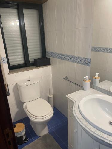 a bathroom with a white toilet and a sink at Casa da Lagoa in Geres