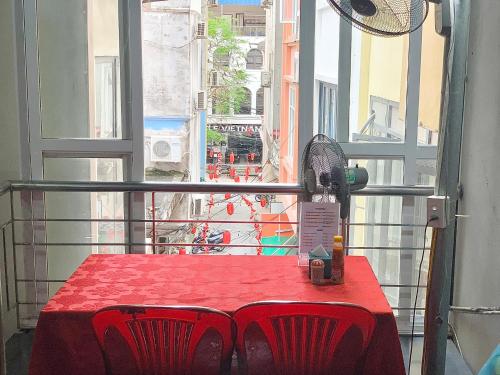 a red table with red chairs in front of a window at Friendly room in Hai Phong