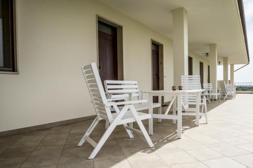 a row of white chairs and a table on a porch at Masseria Gravelle in Turi
