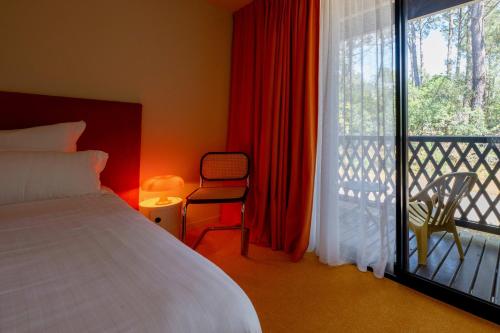 a bedroom with a bed and a balcony with a window at Boutique Hôtel La Baignoire in Lacanau-Océan