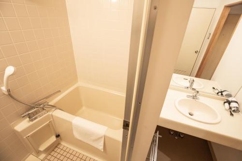 a bathroom with a sink and a tub and a toilet at Motosu Phoenix Hotel in Fujikawaguchiko