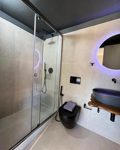 a bathroom with a glass shower and a blue sink at Nidus President in Souda