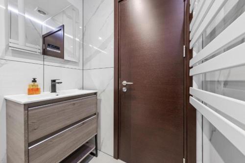 uma casa de banho com um lavatório e uma porta de madeira em Serviced Golders Green Apartment near Camden London - 2 em Londres