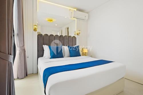 a bedroom with a large bed with blue accents at Lumiere by Kozystay - Dago in Bandung