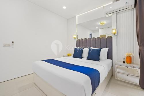 a white bedroom with a large bed with blue pillows at Lumiere by Kozystay - Dago in Bandung