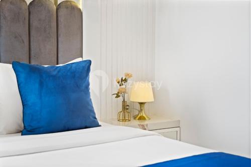 a bed with a blue pillow and a table with a lamp at Lumiere by Kozystay - Dago in Bandung