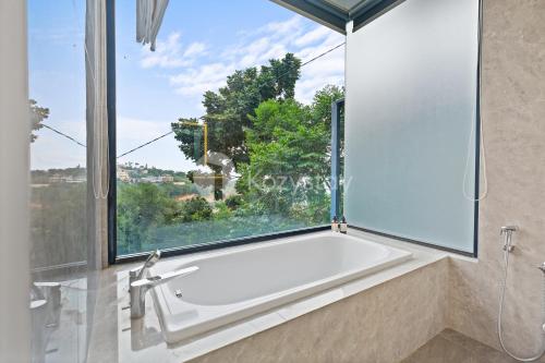 a bath tub in a bathroom with a large window at Lumiere by Kozystay - Dago in Bandung