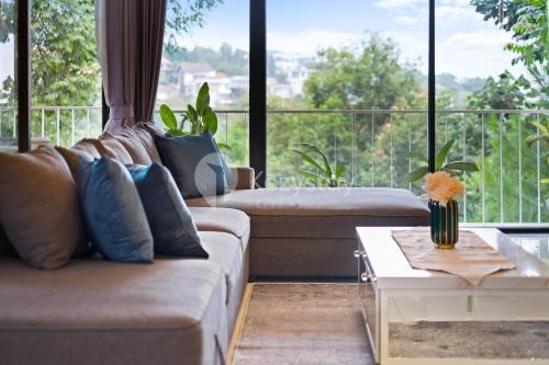 a living room with a couch and a large window at Lumiere by Kozystay - Dago in Bandung