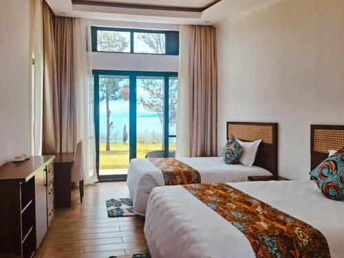 a hotel room with two beds and a window at Eben Lake Kivu cottages and Villas 