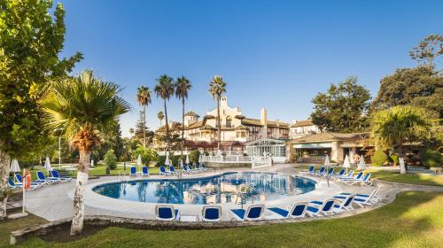 a large swimming pool surrounded by palm trees at Globales Reina Cristina in Algeciras