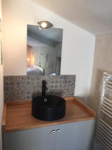 La salle de bains est pourvue d'un lavabo noir et d'un lit. dans l'établissement Les Terrasses de Saint Laurent de Carnols, à Saint-Laurent-de-Carnols