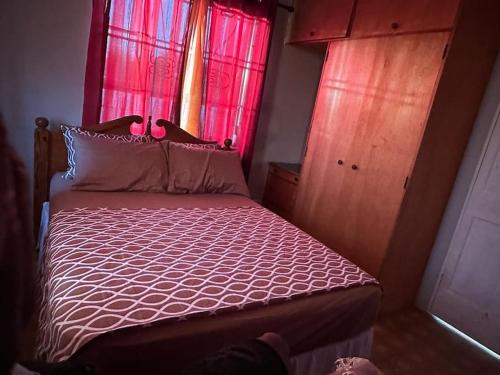 a bedroom with a bed with pink curtains and a window at Moravian Haven in Christ Church