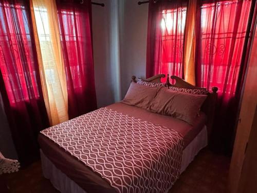 a bedroom with red curtains and a bed with a bed sidx sidx sidx at Moravian Haven in Christ Church