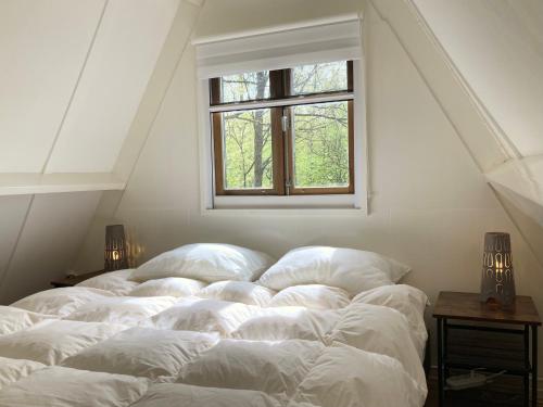 Una cama con sábanas blancas en una habitación con ventana. en Boshuis Bonbon - Chalet in Durbuy, en Durbuy