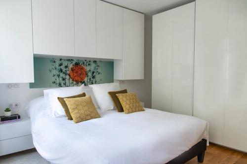 - une chambre avec un lit blanc et des armoires blanches dans l'établissement La Harmonie Eiffel - Walk to Tower, à Paris