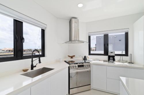 a white kitchen with a sink and a stove at Tanki Leendert 43K in Oranjestad