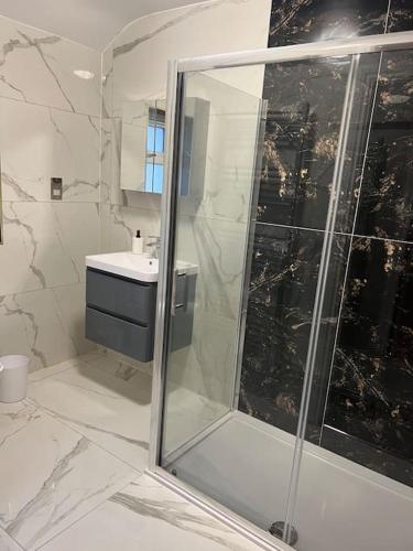 La salle de bains est pourvue d'une douche et d'un lavabo. dans l'établissement Potters Hideout- Warner Bros Studios and London, à Watford