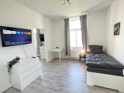 5-Zimmer Apartment in Osnabrück في أوسنابروك: غرفة نوم بسرير وتلفزيون بشاشة مسطحة