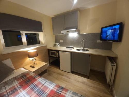 eine kleine Küche mit einem Bett und einem Waschbecken in einem Zimmer in der Unterkunft The Abbey House Hotel in Reading
